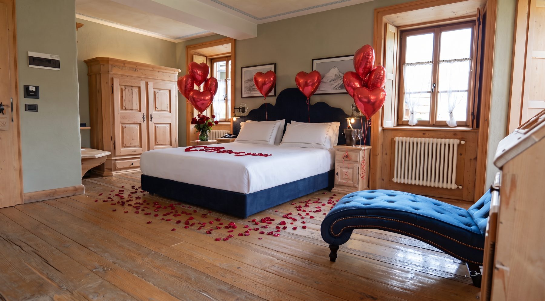 Camera con set-up romantico: petali di rose sul pavimento e palloncini a cuore