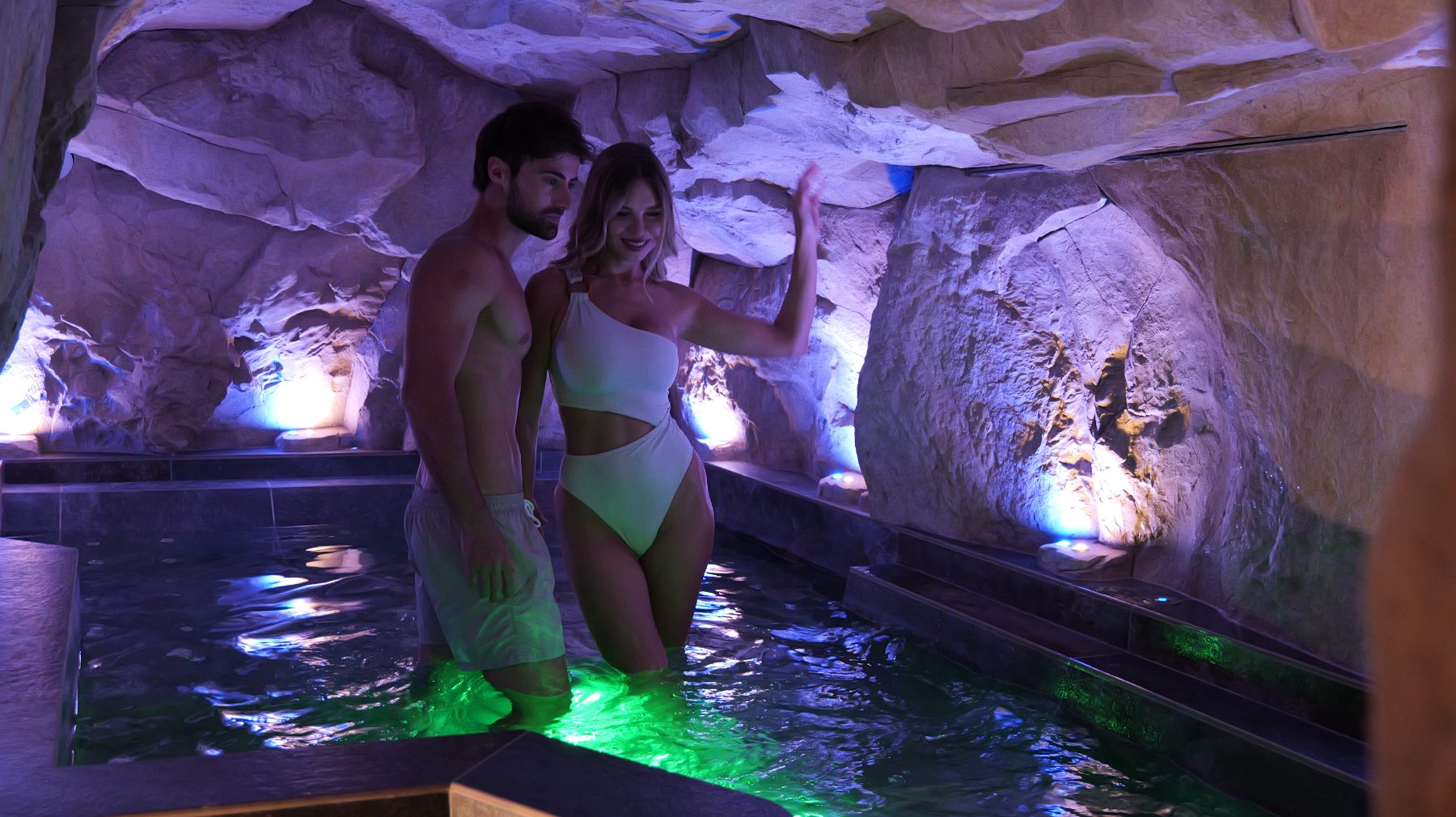 Coppia nella piscina della grotta con luci colorate — spa Sensoria